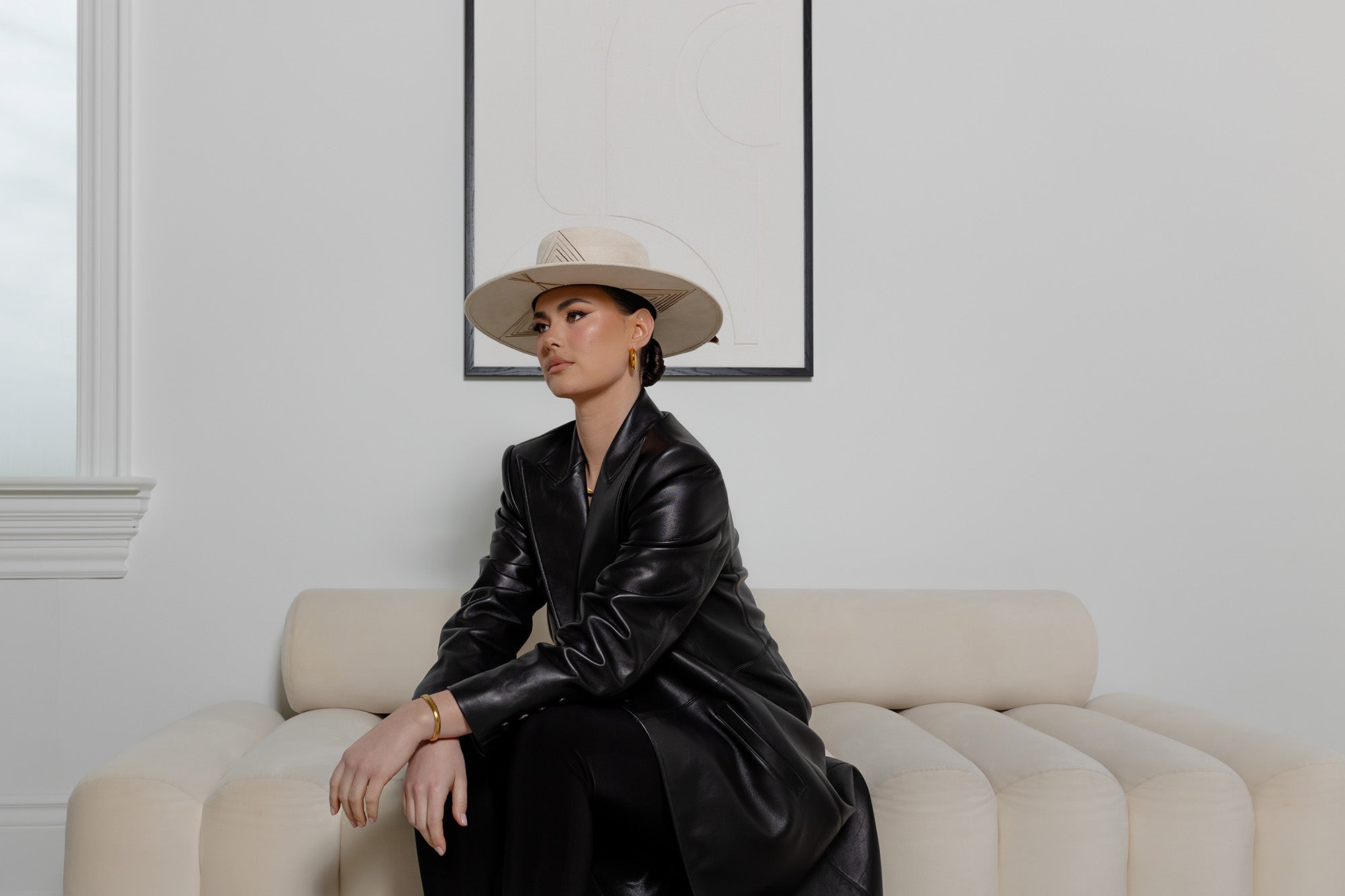 Woman sitting on the couch wearing a hat and jewellery | Lindsay King Luxury Fashion and Inspired Home Goods